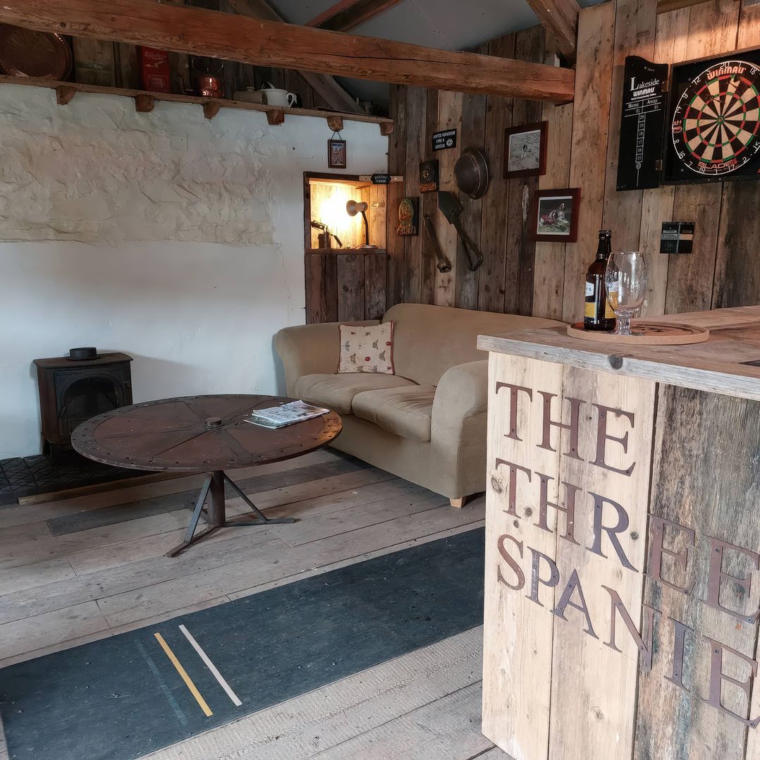A snug with a sofa and a wood stove at The Three Spaniels Shepherds Hut in Lampeter