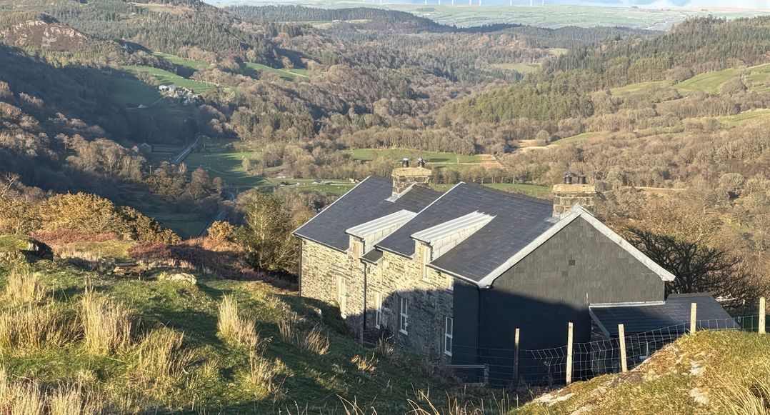 A house with a roof and chimney on a hillside at Ty Llugwy in Capel Curig near Betws-Y-Coed