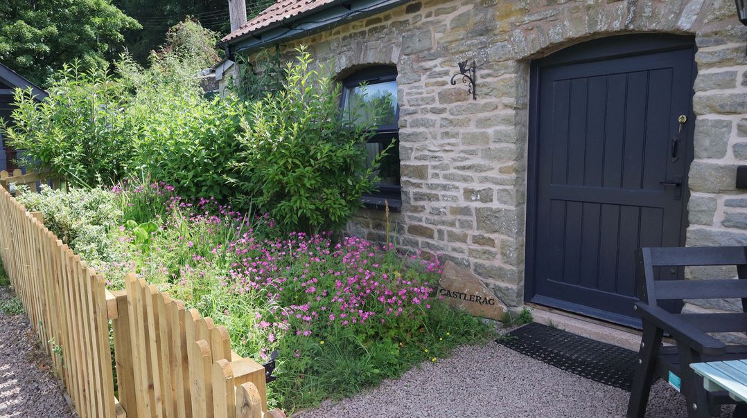 An outdoor area with flowers and a wooden gate at Castle Rag in Parkend