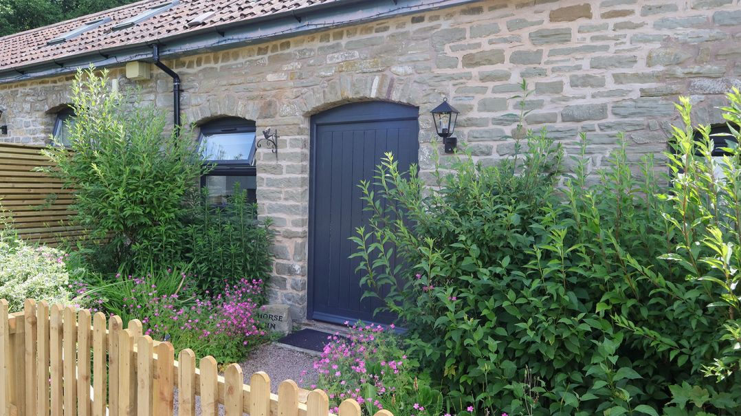 An entrance with plants and a wooden fence at Horse Gin in Parkend