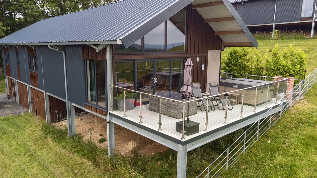 An outdoor area with decking, chairs and a hot tub at Bwncath in Garthmyl