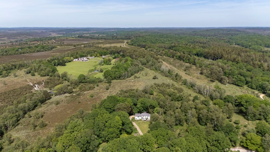 An aerial view of a house surrounded by trees and fields at Primrose Spinney in Highwood near Ringwood