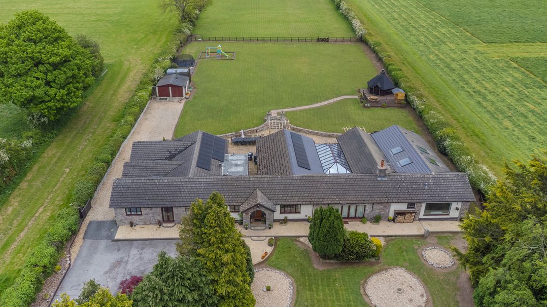 An aerial view of a house with a garden and playground at Brookway Lodge, Caerwys