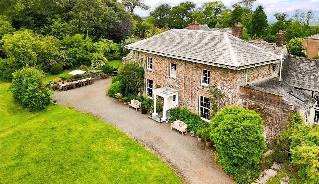 An outdoor view of a house with a garden and seating area at Parnacott in Holsworthy