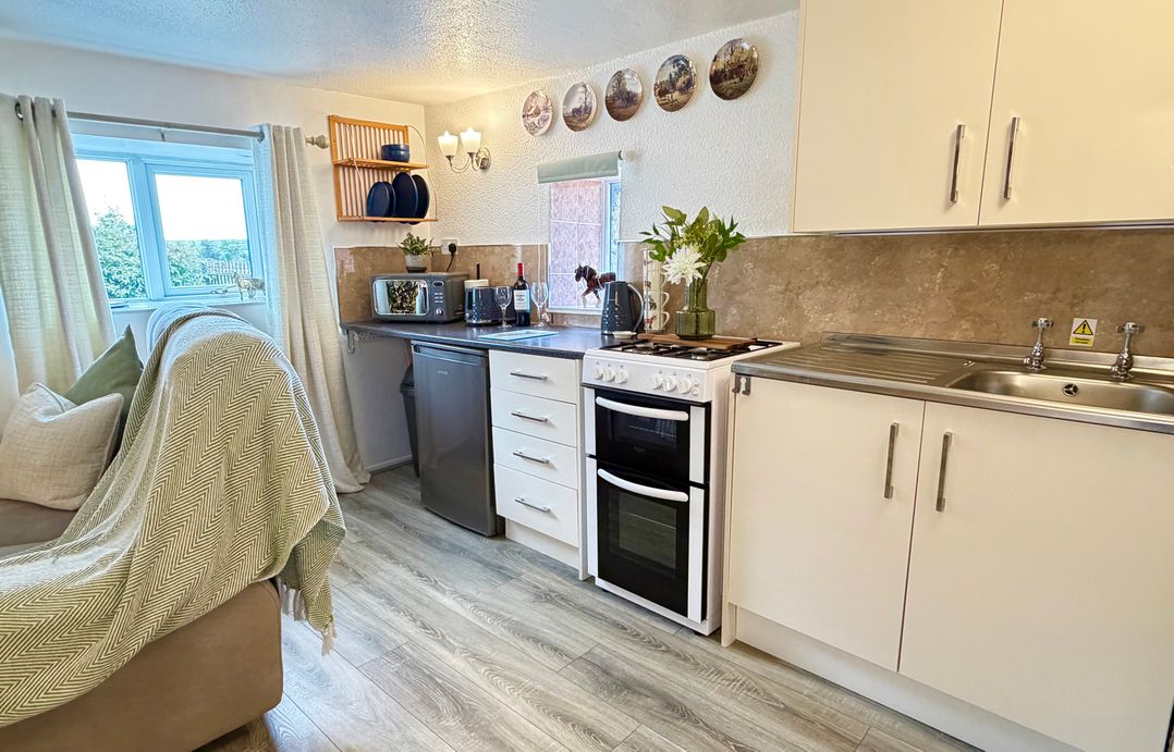 A kitchen with a window, stove, fridge, and sink at Wayside Farm Cart Cottage Cloughton near Burniston