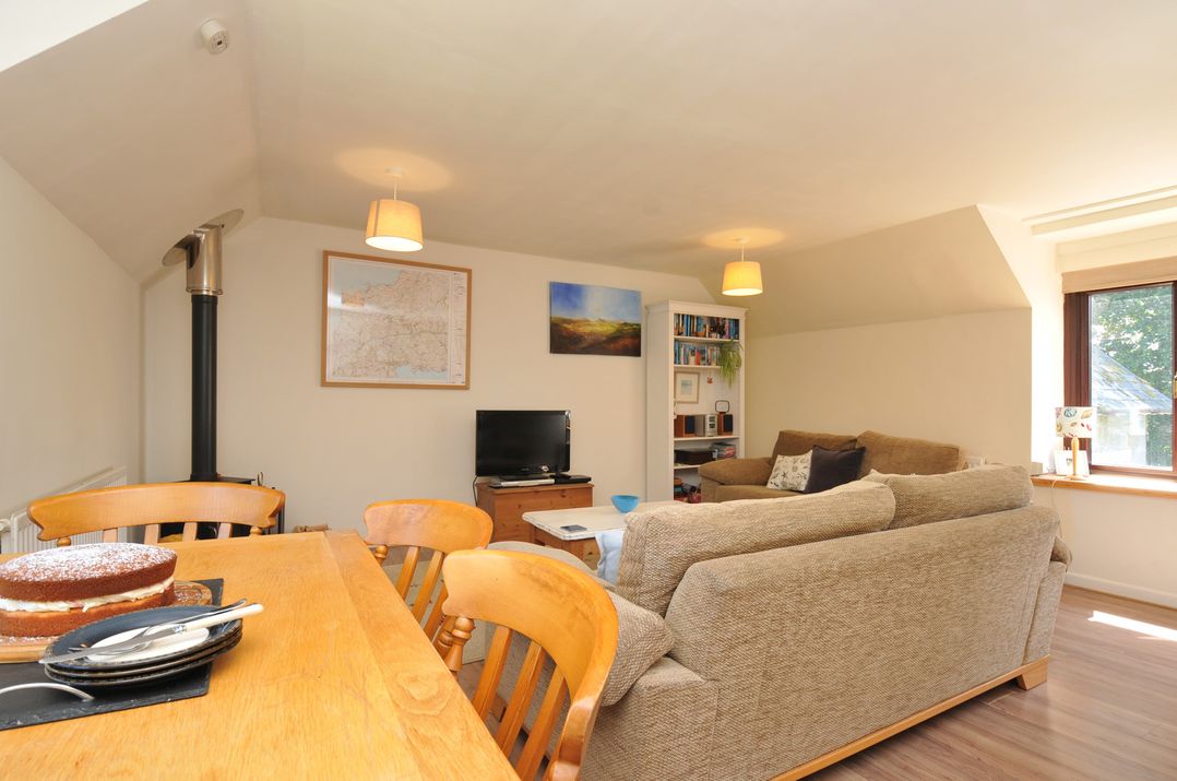 A living room with a dining table and television at The Mews in Blisland