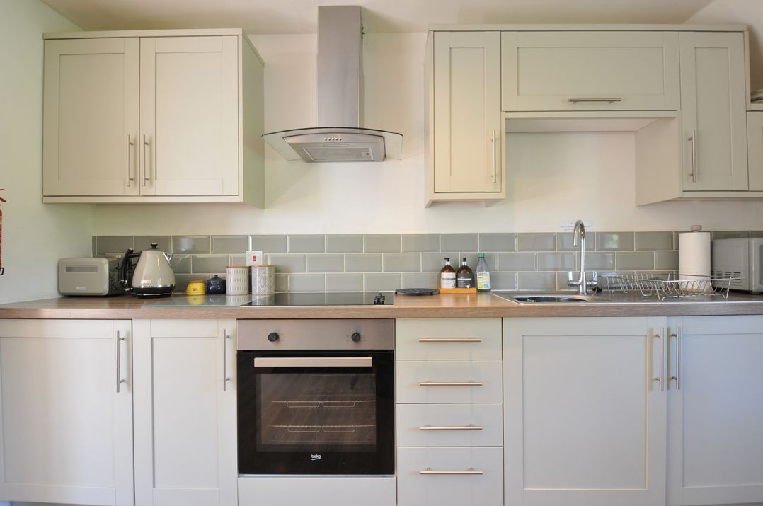 A kitchen with cabinets, oven, sink, and appliances at The Mews in Blisland