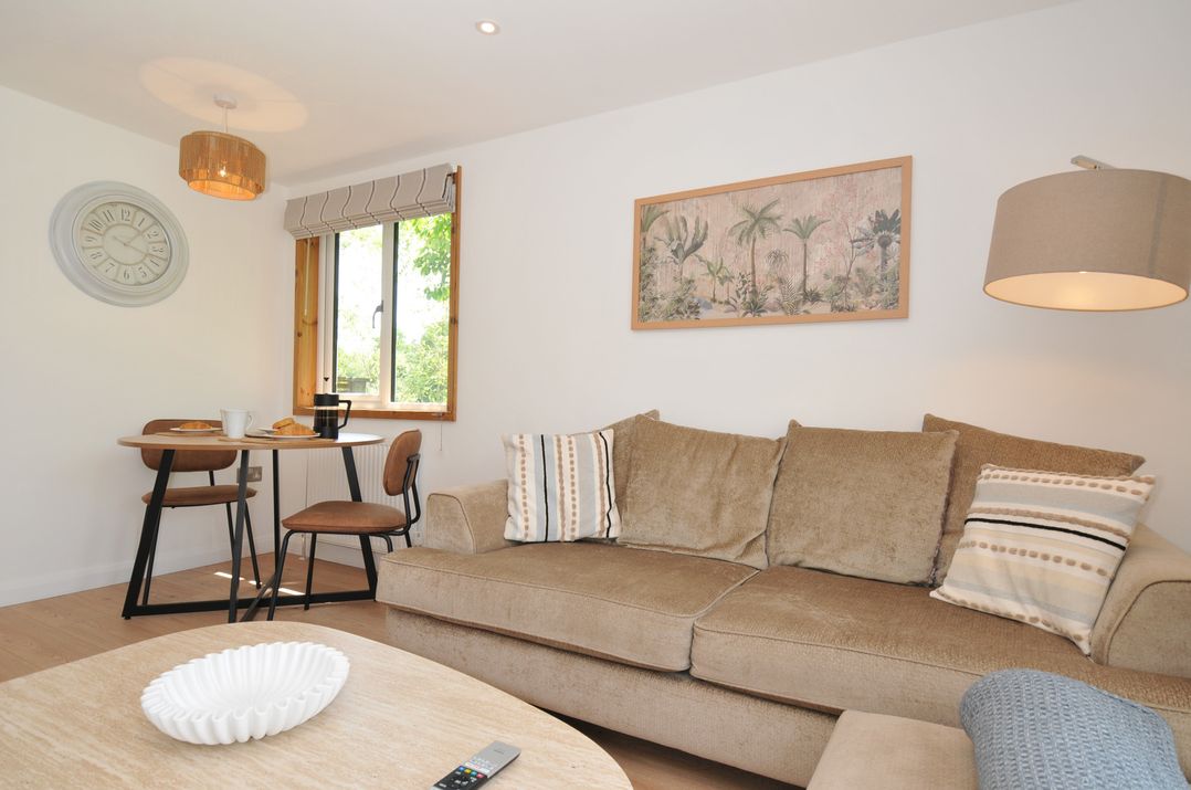 A living room with a sofa and dining area at 12 Meadow Retreat in Dobwalls