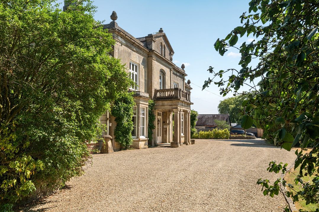 A house with a balcony and gravel driveway at Milton Manor in Milton On Stour