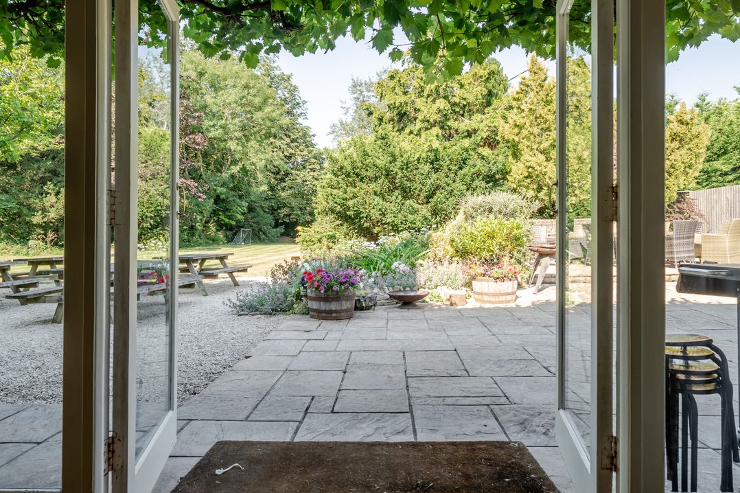 A garden with flower pots and picnic table at Milton Manor in Milton On Stour