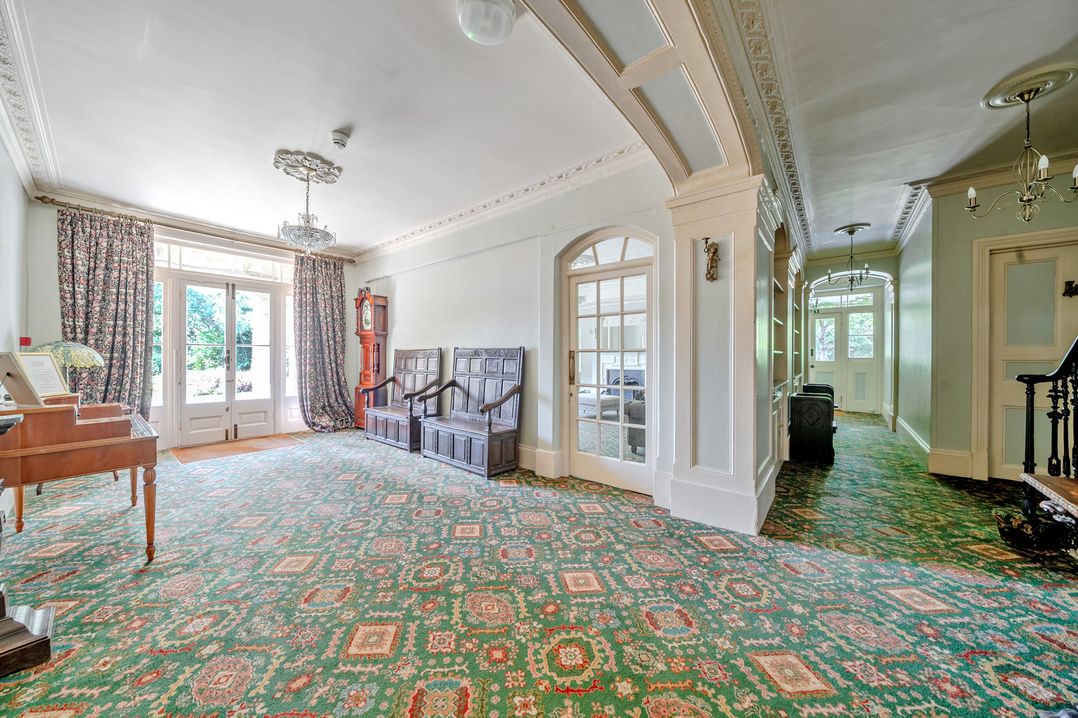 A living room with a chandelier and wooden furniture at Milton Manor in Milton On Stour