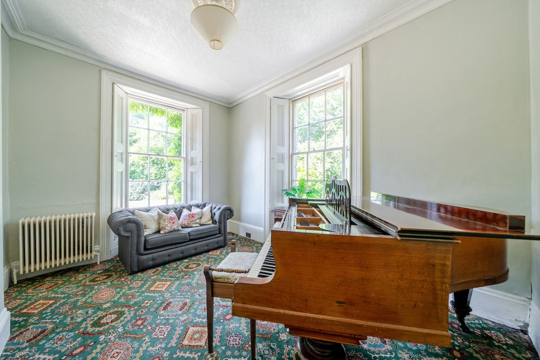 A living room with a sofa and piano at Milton Manor in Milton On Stour