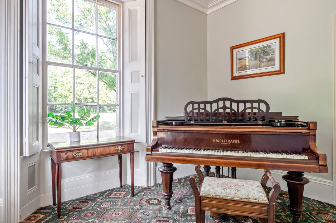 A music room with a piano and table at Milton Manor in Milton On Stour