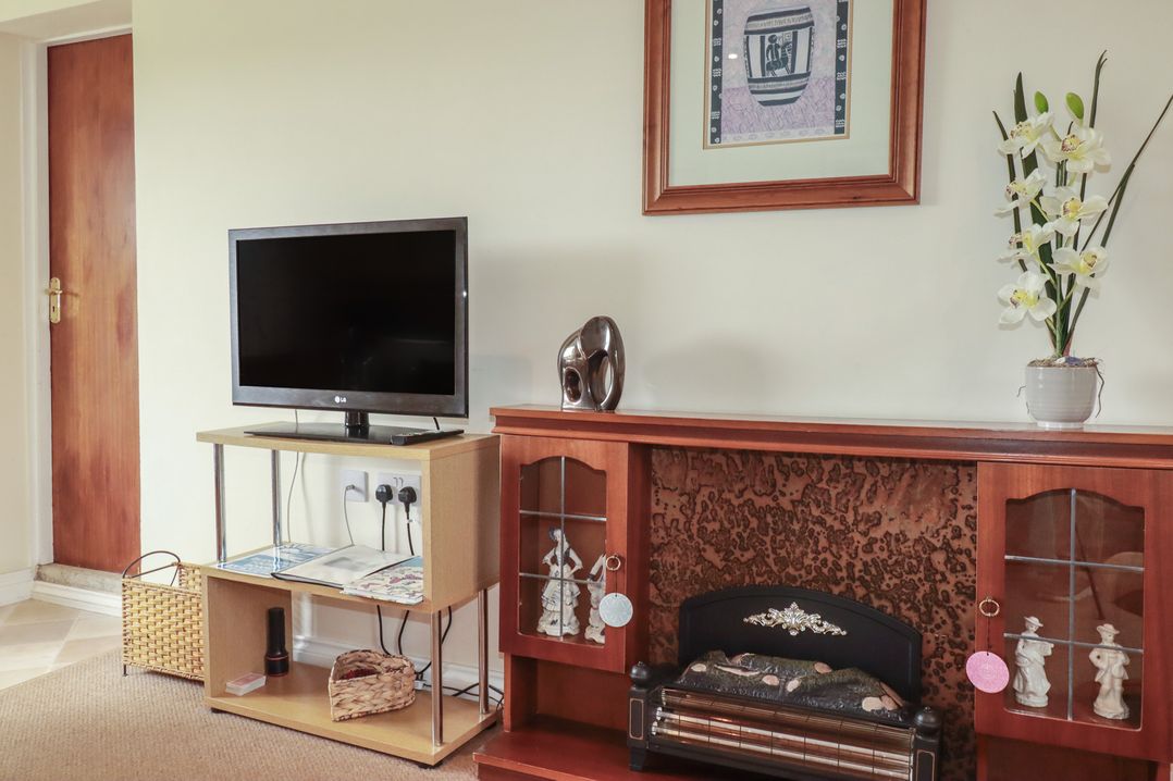 A living room with a television and decorative items at Little Lanes in Boscastle