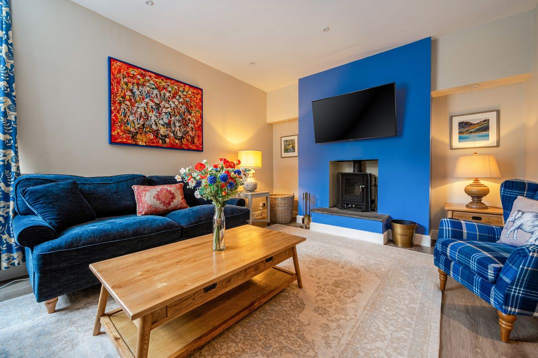 A living room with a sofa, coffee table, and fireplace at Home Farmhouse at the Graythwaite Estate near Hawkshead