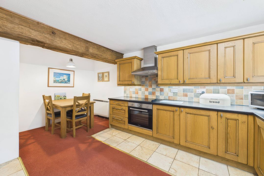 A kitchen with wooden cabinets and dining table at The Roundhouse in Warbstow