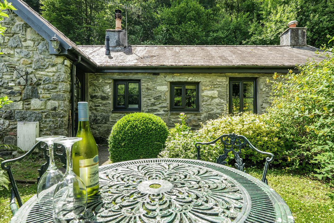 A table and chairs with wine and glasses at Tyn Y Ffynnon in Betws-Y-Coed