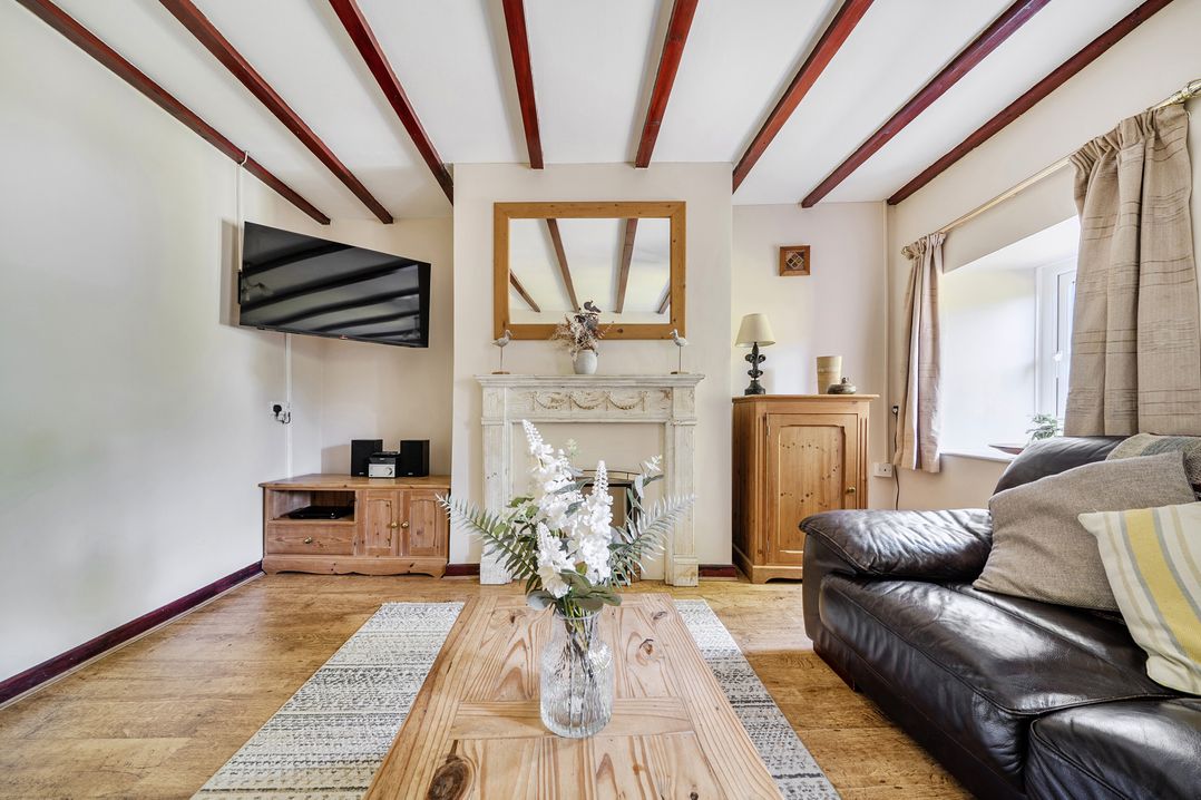 A living room with a television, fireplace, and wooden furniture at Tyn Y Ffynnon in Betws-Y-Coed