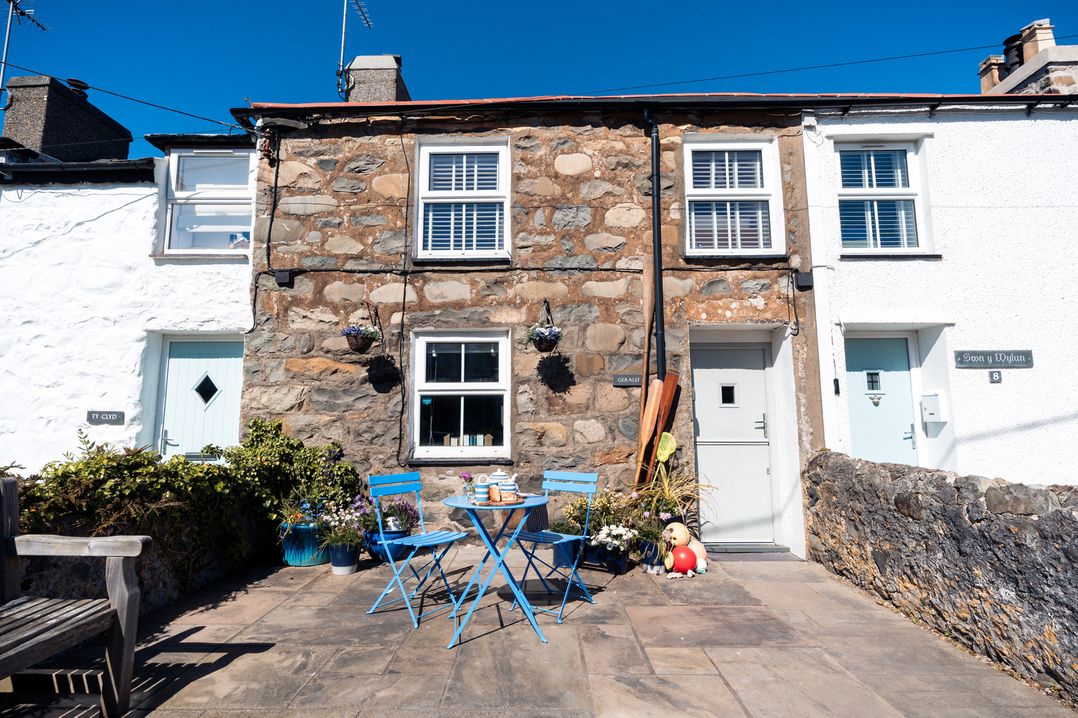 An outdoor patio with blue furniture and plants at Gerallt in Morfa Nefyn
