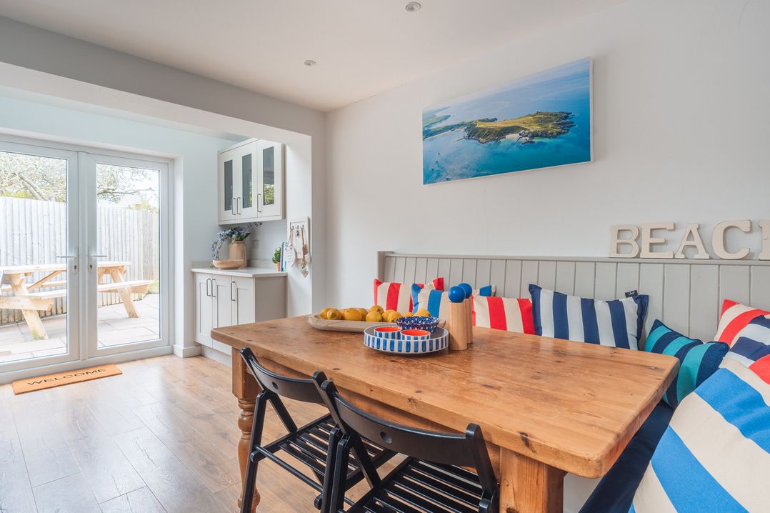 A dining room with a wooden table and striped cushions at Gerallt in Morfa Nefyn
