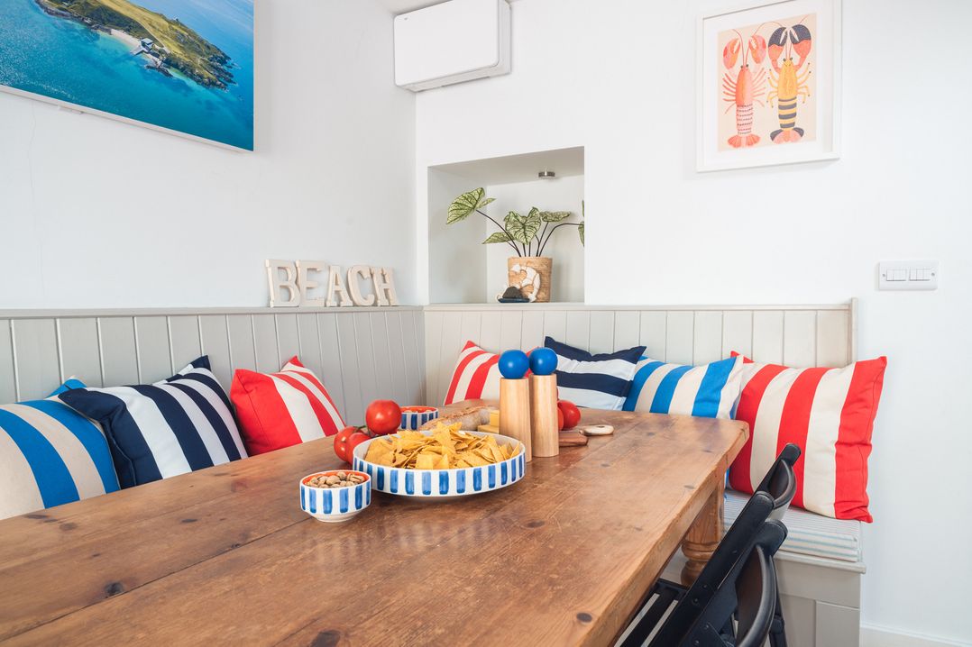 A dining room with a table and decorative cushions at Gerallt in Morfa Nefyn