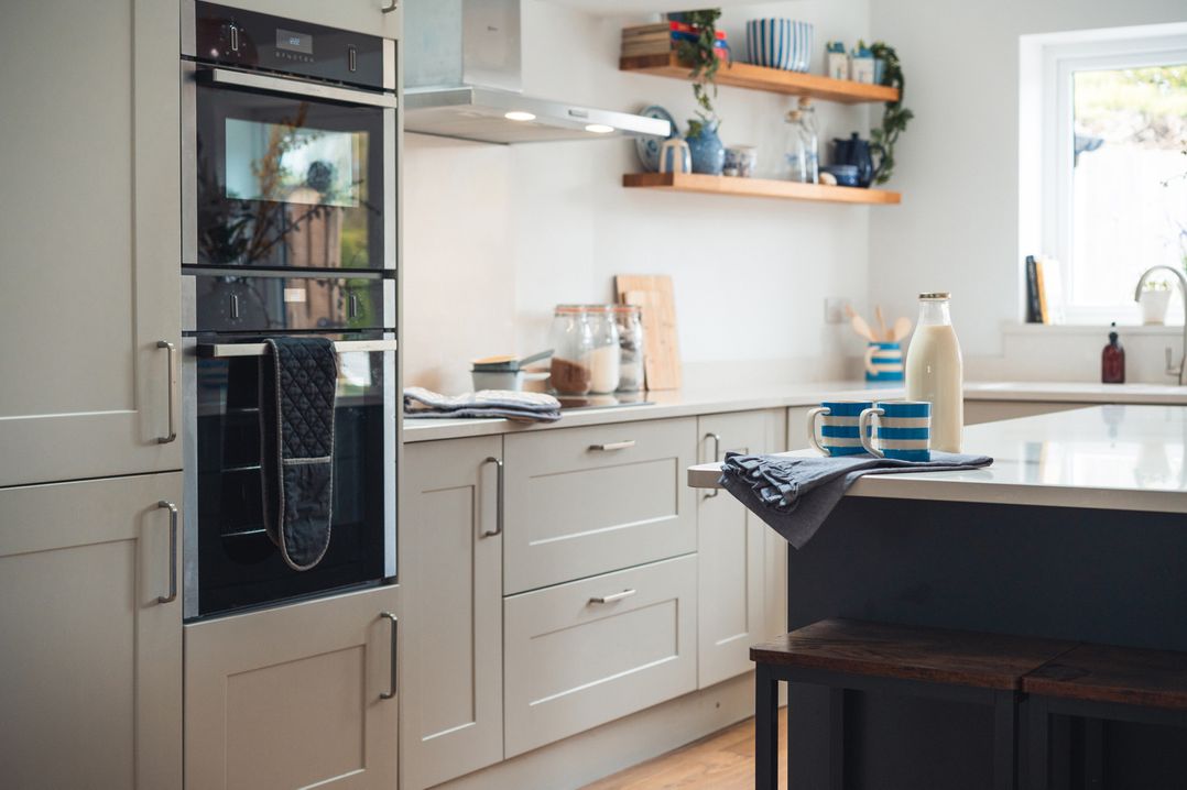 A kitchen with an oven, cups, and a milk bottle at Gerallt in Morfa Nefyn