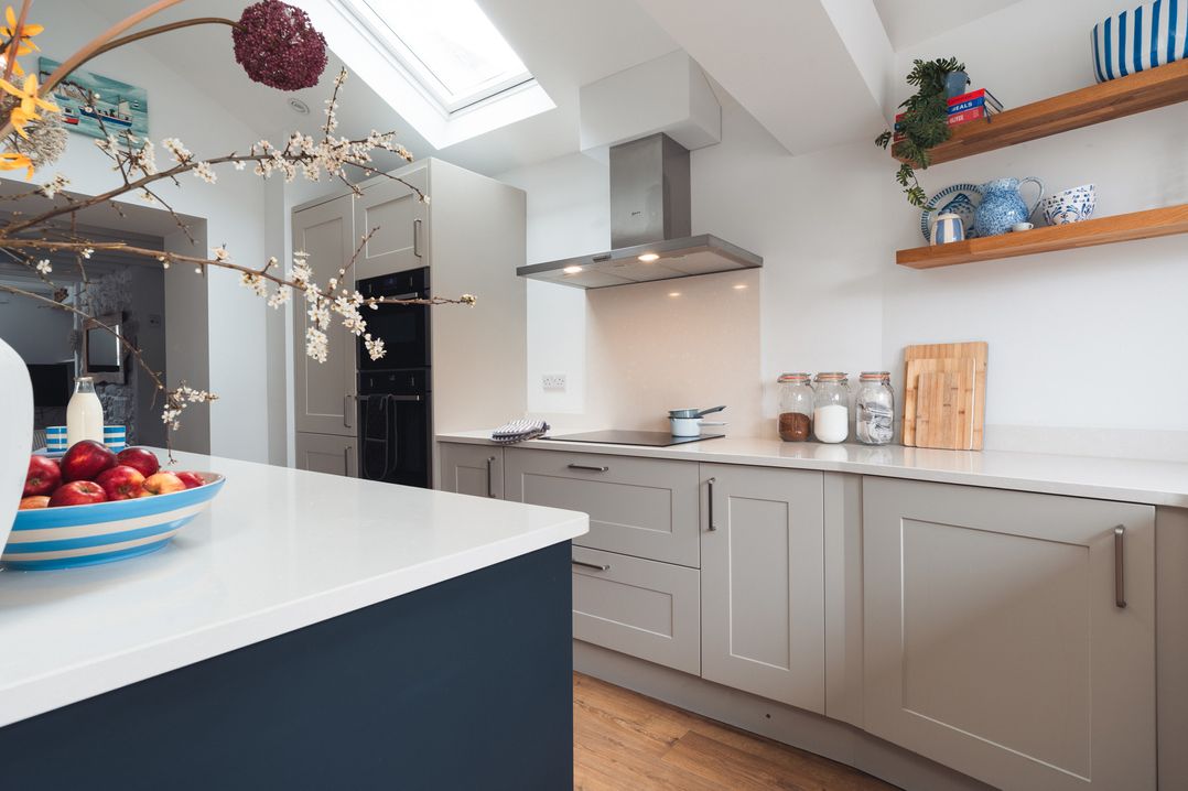 A kitchen with a kitchen island and bowl of apples at Gerallt in Morfa Nefyn