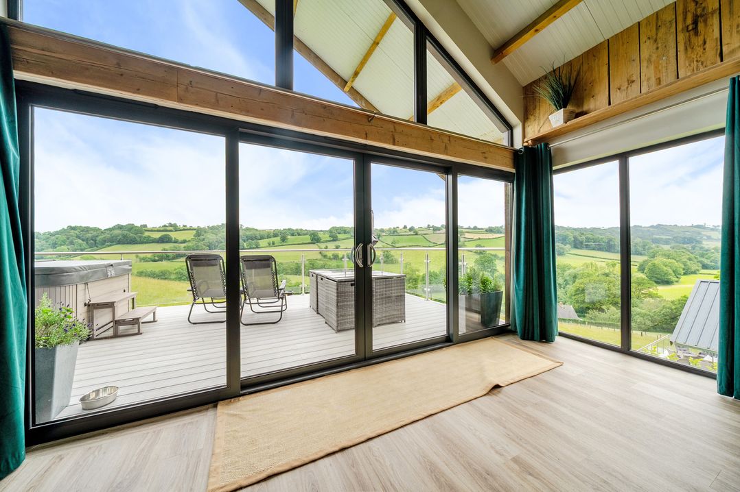 A living room with sliding glass doors leading to the deck at Bwncath in Garthmyl