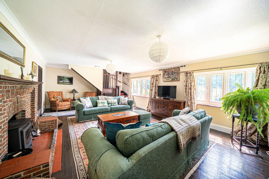A living room with green sofas and a fireplace at Primrose Spinney in Highwood near Ringwood