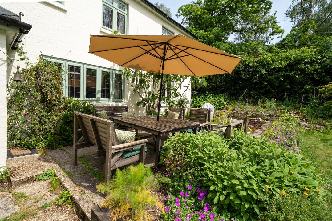 A garden with dining table and umbrella at Primrose Spinney in Highwood near Ringwood