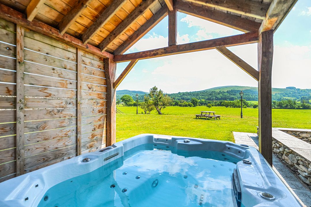 A hot tub under a wooden structure in an outdoor area at The Barn in Corwen