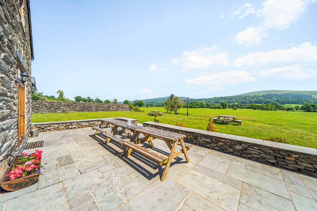 An outdoor space with a picnic table and views of grass at The Barn in Corwen