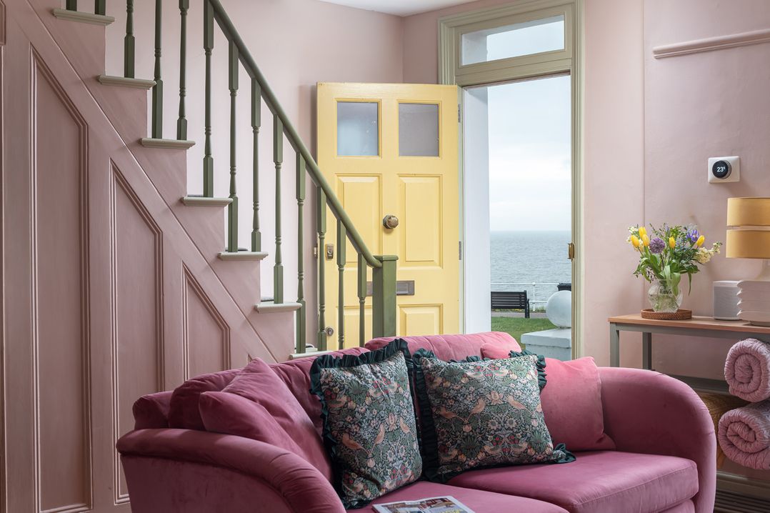 A living room with a staircase and yellow door at Astondene, East Cliff, Southwold