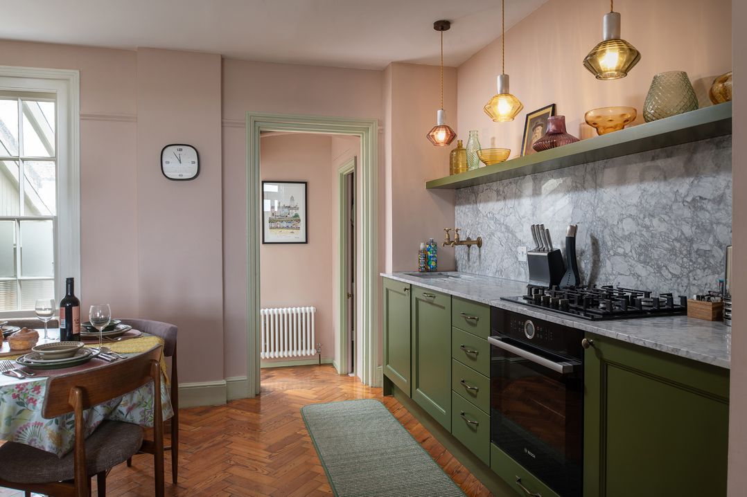 A kitchen with green cabinets and a dining table at Astondene, East Cliff in Southwold
