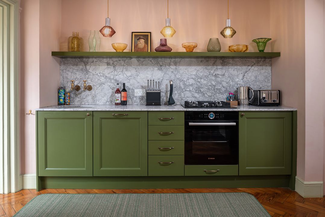 A kitchen with green cabinets and marble countertop at Astondene, East Cliff Southwold