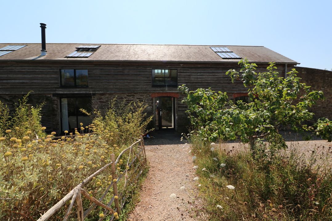 A building with windows and a door in a garden at The Milking Shed in Bantham