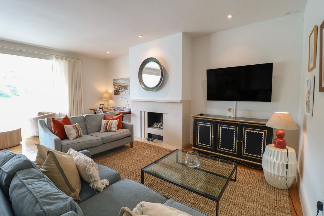 A living room with a sofa, armchair, coffee table, and television at 22 Dart Marina in Dartmouth