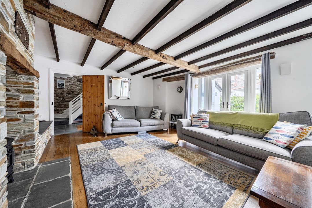 A living room with sofas and a fireplace at Mews Cottage in Tintagel