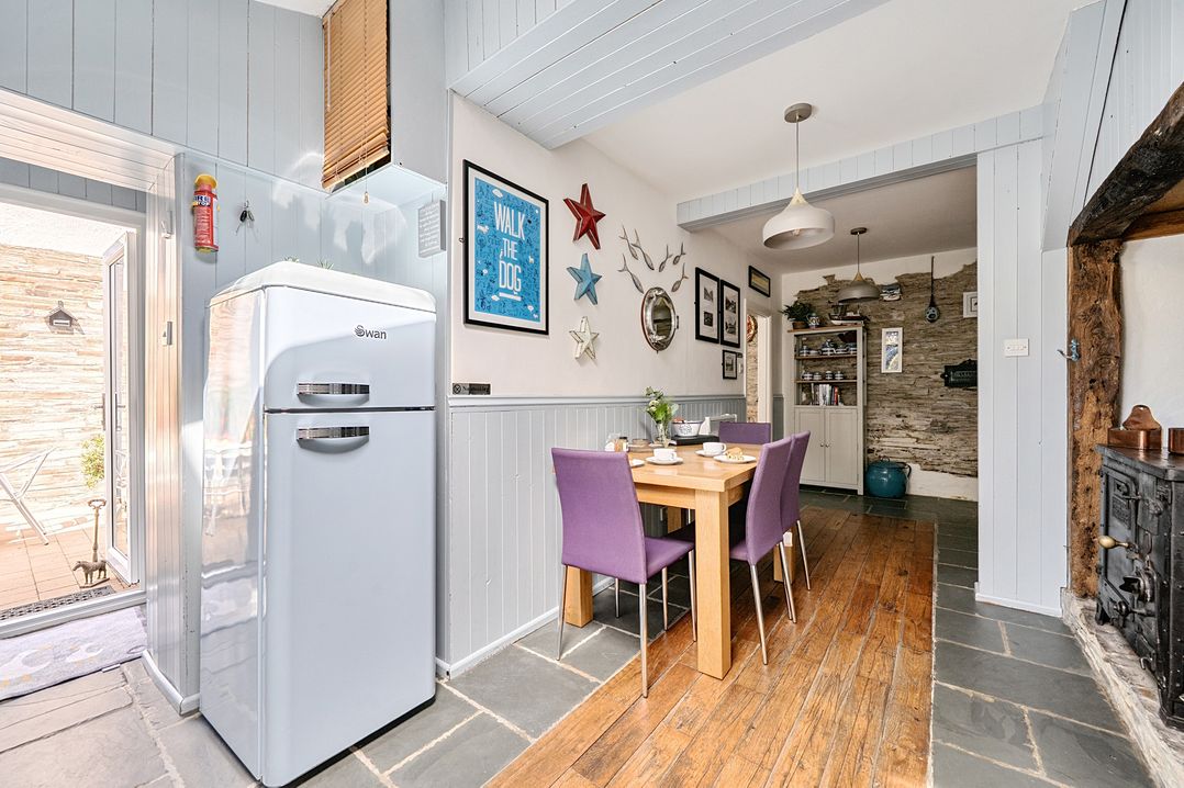 A dining room with a refrigerator and a table at Mews Cottage in Tintagel