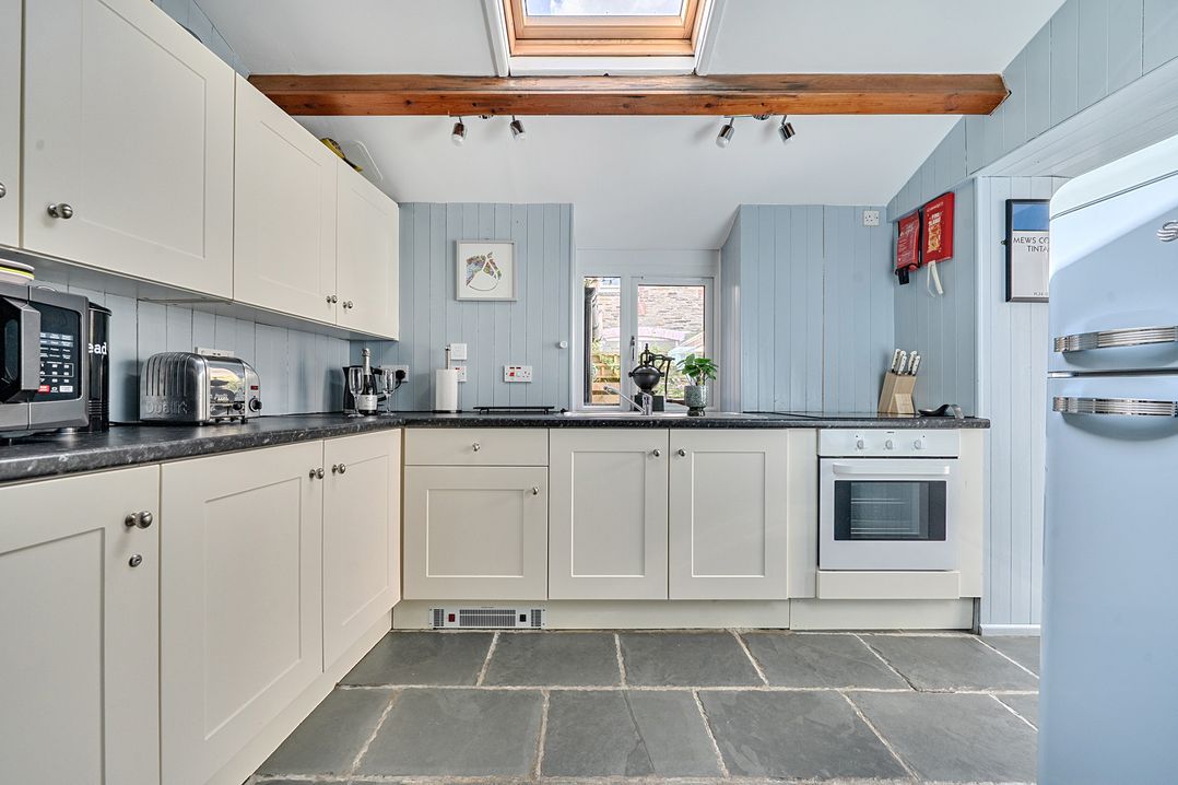 A kitchen with cabinets, a stove, and a toaster at Mews Cottage in Tintagel