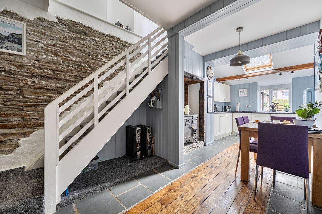 A kitchen with stairs and a dining table at Mews Cottage in Tintagel