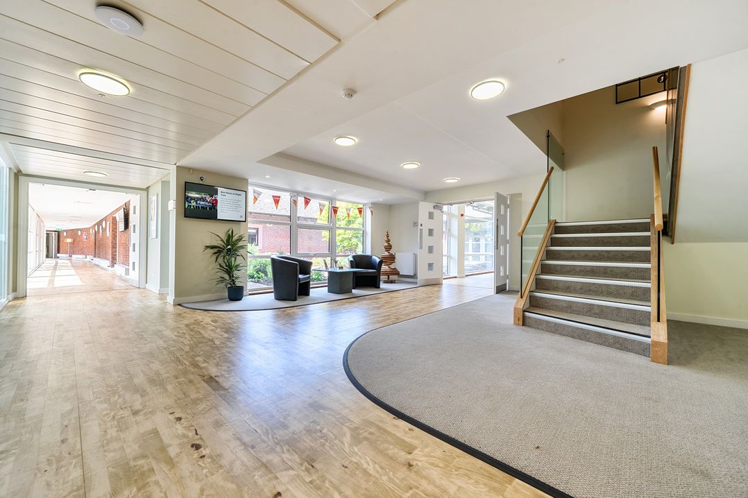 A lobby with a staircase, chairs, table, and potted plant at Jubilee First-floor Double Bedroom Penrith