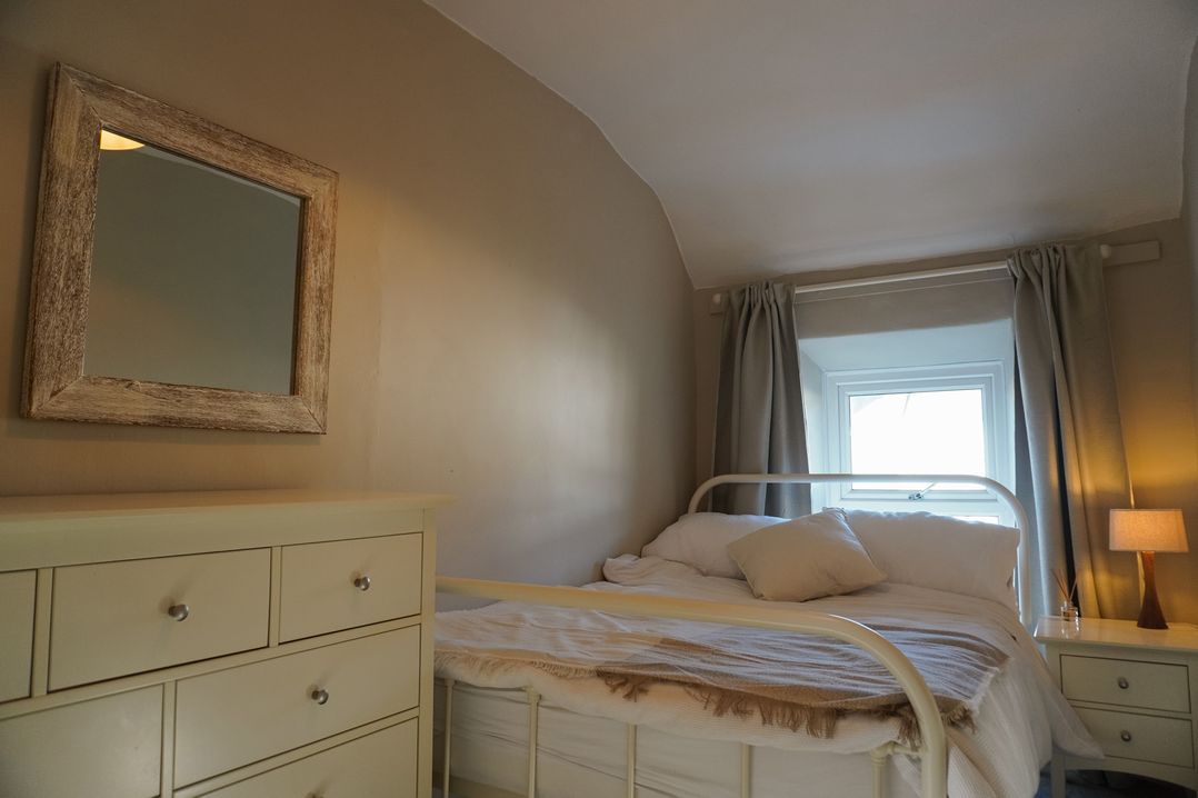 A bedroom with a bed and dresser at Rhianfa in Newborough