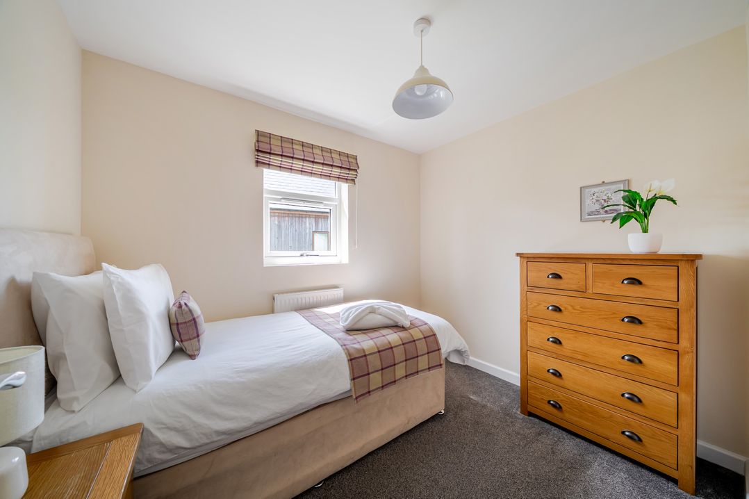 A bedroom with a single bed and dresser at Paddington Lodge near Brigg