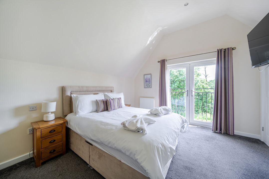 A bedroom with a bed and balcony doors at Paddington Lodge Near Brigg