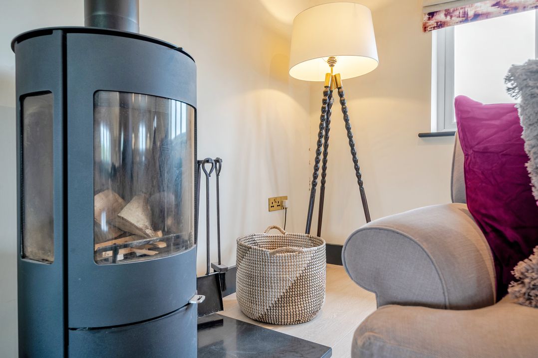 A living room with a fireplace and lamp at Bell House in Llanfechell