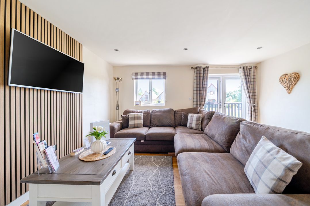 A living room with a sectional sofa and television at James Ville Marina Lodge 8 in Brigg