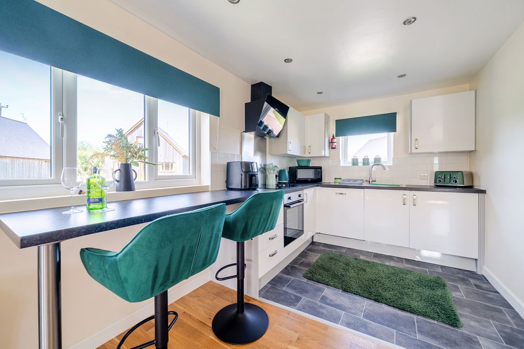 A kitchen with bar stools at James Ville Marina Lodge 22 in Brigg