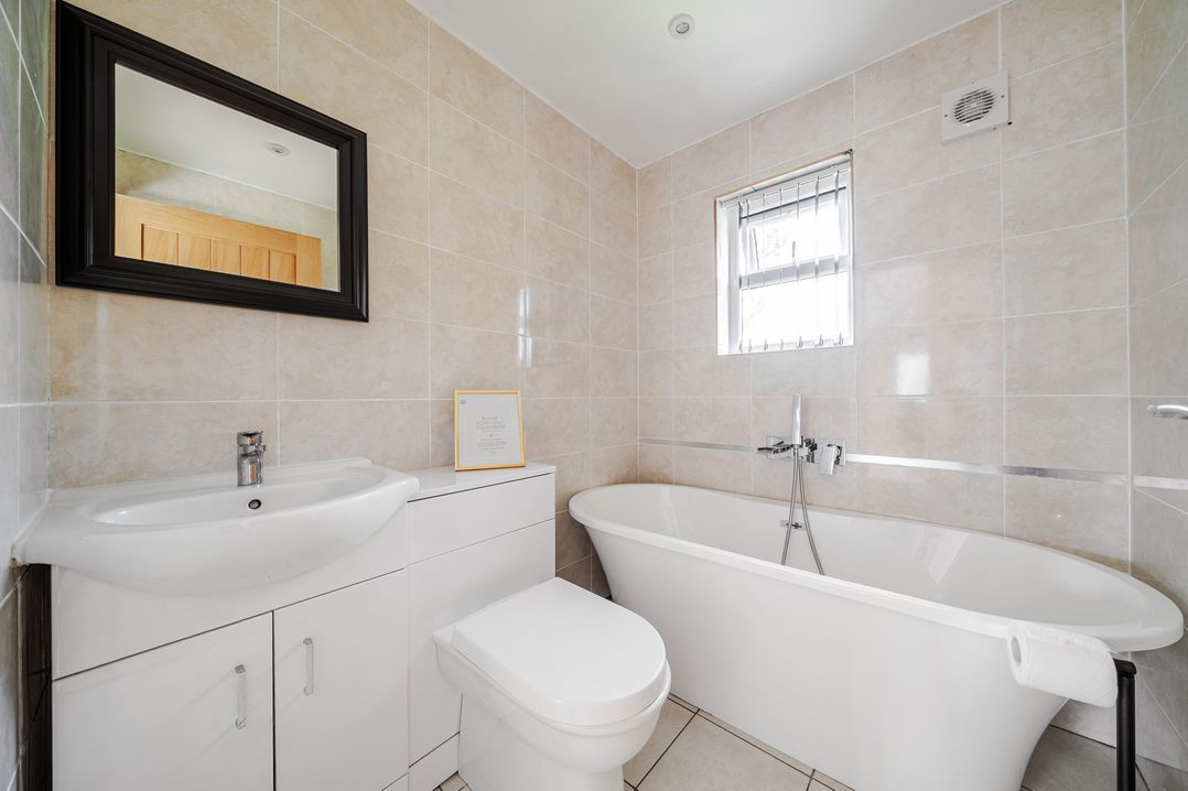 A bathroom with a sink, toilet, bathtub, and mirror at Poker Lodge Near Brigg