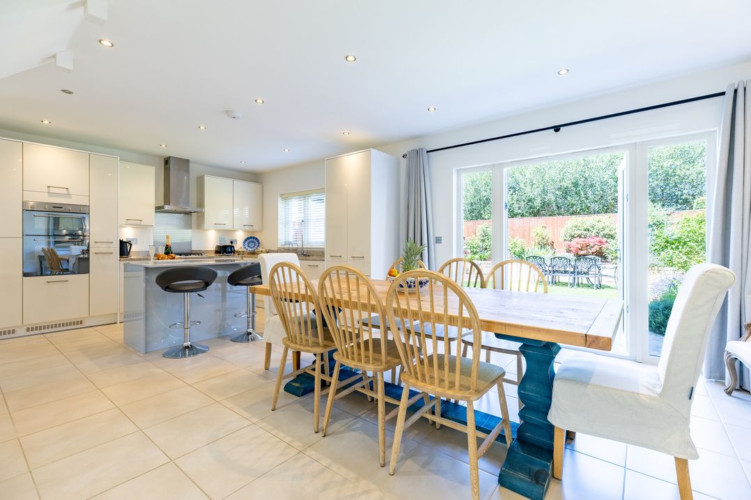 A kitchen with a dining table and bar stools at Old Railway Close in Lechlade-On-Thames